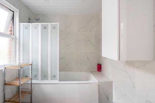 un bagno bianco con vasca e mobile bianco di Maybury Maison a Woking