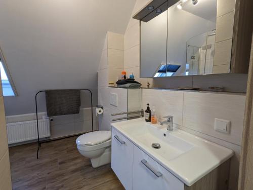 a white bathroom with a toilet and a sink at Großes Zimmer mit eigenem Bad/Flur in Emsbüren