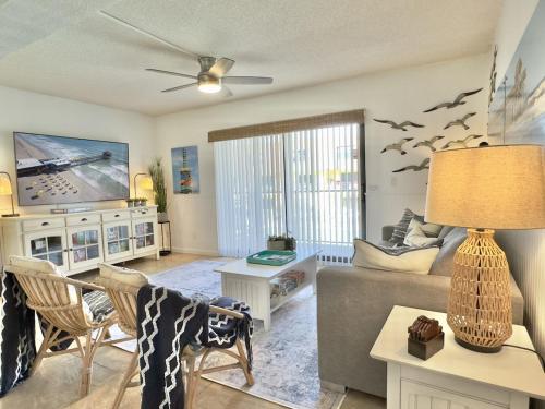 a living room with a couch and a tv at Pier Pressure Beachfront Wpool in Cocoa Beach