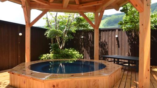 uma banheira de hidromassagem num deque de madeira com uma pérgola em Villa Schole Hakuba - Vacation STAY 19519v em Yotsuya