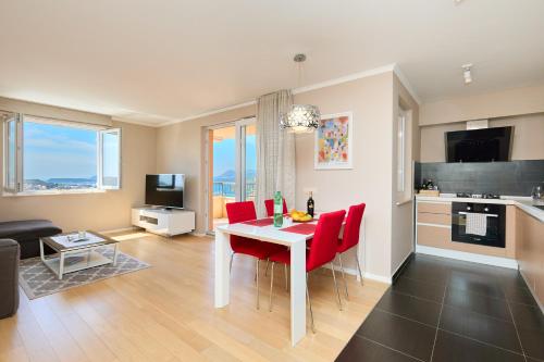 eine Küche und ein Wohnzimmer mit einem Tisch und roten Stühlen in der Unterkunft Polina's Sunset Apartment in Dubrovnik