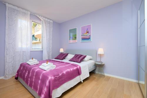 ein Schlafzimmer mit einem lila Bett mit Handtüchern darauf in der Unterkunft Polina's Sunset Apartment in Dubrovnik