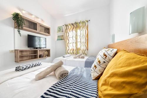 1 dormitorio con 2 camas y TV en la pared en BUNGALOWS LOS ARCOS 77 en San Bartolomé