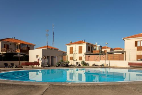 una gran piscina en un patio con casas en Villa Calderón Hondo. Top design , views and pool Lajares-Corralejo, en Corralejo