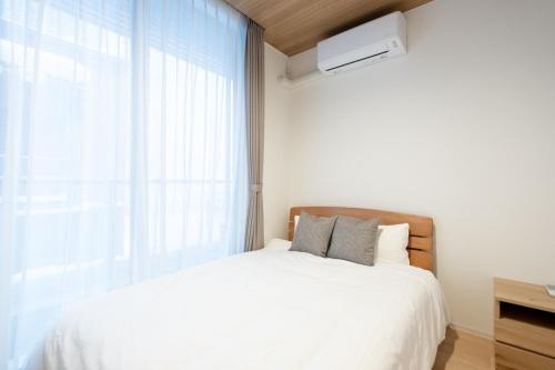 um quarto com uma cama branca e uma janela em Ｑｕｅｅｎｓ Ｐａｒｋ ＣＫ ＶＩＬＬＡＧＥ Ｎｉｓｅｋｏ Ｈｉｒａｆｕ Ｉ - Vacation STAY 14145 em Niseko