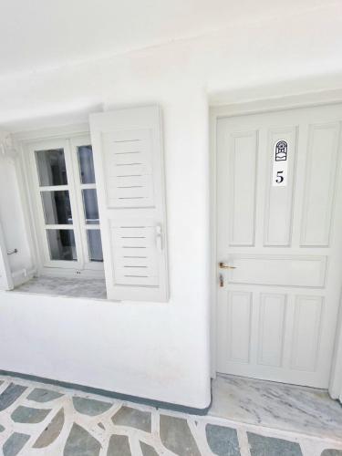 a white room with two doors and a rug at Joannes Vacation Rooms in Adamas