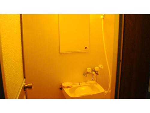 W łazience znajduje się żółta umywalka i lustro. w obiekcie Petit Hotel Koizumi - Vacation STAY 85672v w mieście Tōya-ko