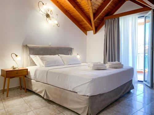 a bedroom with a large white bed with a chandelier at Rouchotas Apartments in Argostoli
