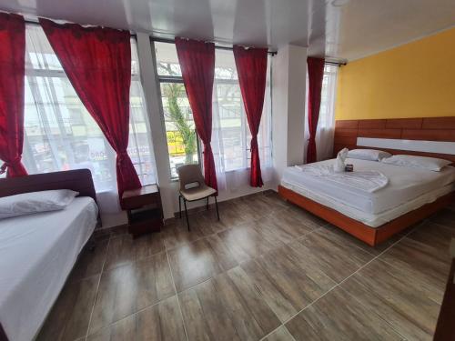 ein Schlafzimmer mit zwei Betten und roten Vorhängen in der Unterkunft Hotel las Corocoras del llano in Villavicencio
