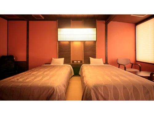 two beds in a room with red walls at Saikatei Jidaiya - Vacation STAY 96315v in Kaminoyama