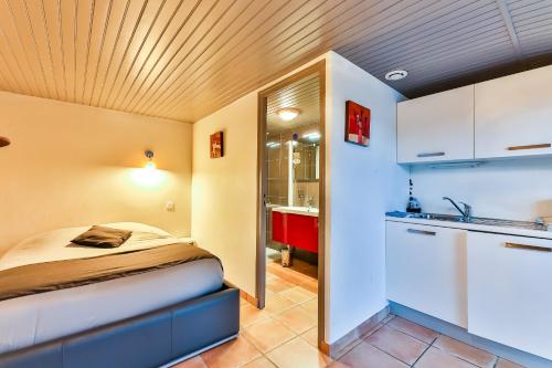 ein kleines Schlafzimmer mit einem Bett und einer Küche in der Unterkunft Gite - Studios Marie Barrault in Les Herbiers