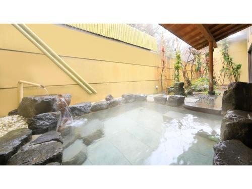 a hot tub in a yard with rocks at Saikatei Jidaiya - Vacation STAY 96439v in Kaminoyama