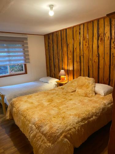 a bedroom with two beds and a wooden wall at Ruka Pucón Hostel in Pucón