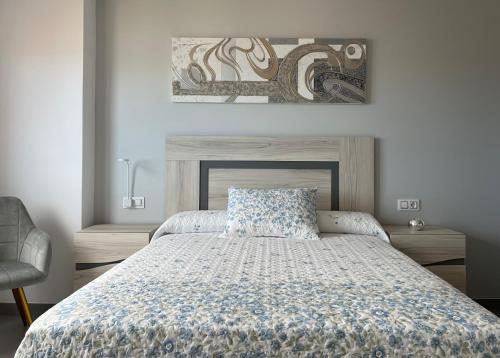 Apartamentos Maria de Lucia- Ático في Arou: غرفة نوم بسرير لحاف ازرق وبيض