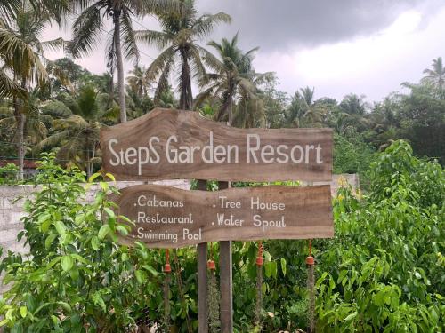 a sign for a garden resort with palm trees in the background at Steps Garden Resort in Negombo