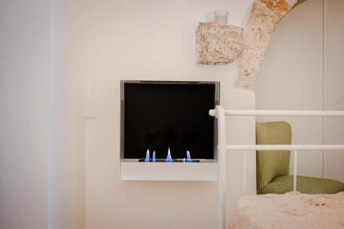 a flat screen tv sitting on a wall with a chair at Ad un passo da Cisternino - Trulli con Camino, Foresta e BBQ in Cisternino