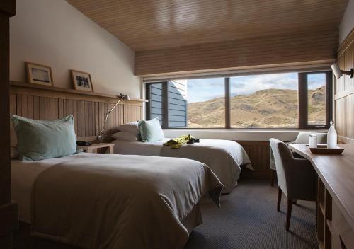 a hotel room with two beds and a large window at Explora en Torres del Paine - All Inclusive in Torres del Paine