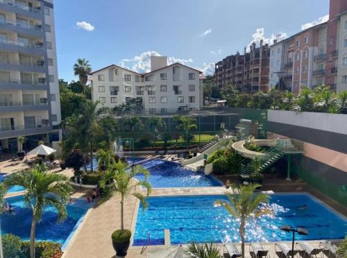 a large swimming pool with palm trees and buildings at Veredas do Rio Quente Hotel Service in Rio Quente