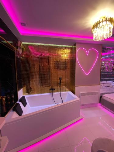 bañera en una habitación con iluminación rosa en Apartament "Love Paradise" Centrum z dużą wanną dla Dwojga, en Gniezno