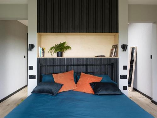 a bedroom with a blue bed with orange pillows at Grand Designs Chess Valley Project - Rickmansworth in Rickmansworth