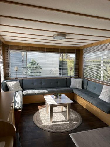 a living room with a blue couch and a table at Gezellige STACARAVAN met groot, zonnig terras! in Belt-Schutsloot