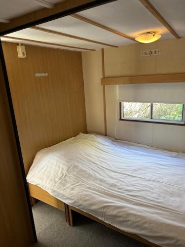 Cama pequeña en habitación pequeña con ventana en Gezellige STACARAVAN met groot, zonnig terras!, en Belt-Schutsloot