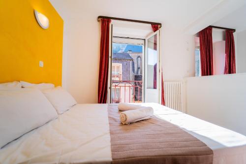 a bedroom with a large white bed with a window at Céline hôtel le miridan in Plombières-les-Bains