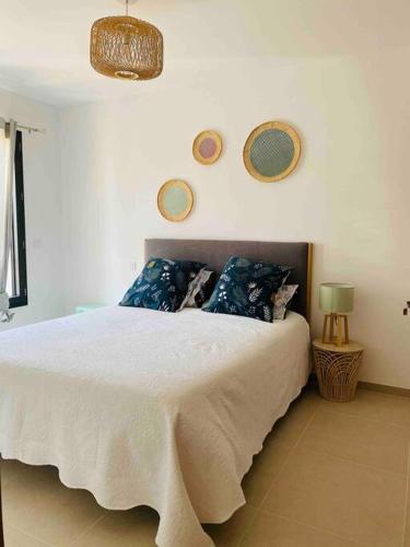 une chambre avec un grand lit blanc avec des oreillers bleus dans l'établissement T2 neuf 4 personnes avec piscine/terrain tennis, à Porto-Vecchio