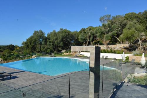 une grande piscine avec une terrasse en bois et un ciel clair dans l'établissement T2 neuf 4 personnes avec piscine/terrain tennis, à Porto-Vecchio