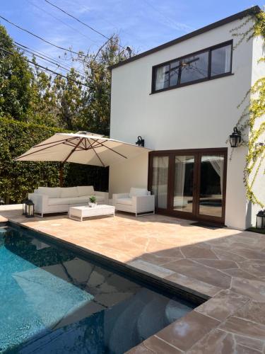 uma casa com uma piscina e um pátio com um guarda-sol em The Cozy Villa em Los Angeles