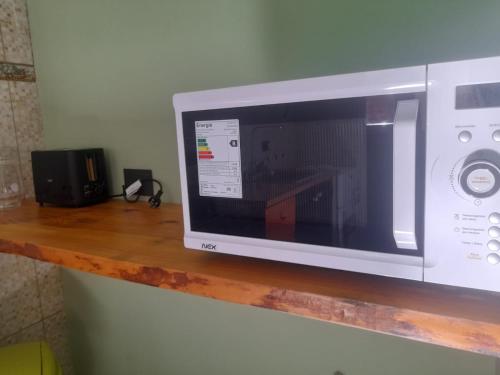 un microondas en la parte superior de una estantería de madera en Apartamentos km4, en Comodoro Rivadavia
