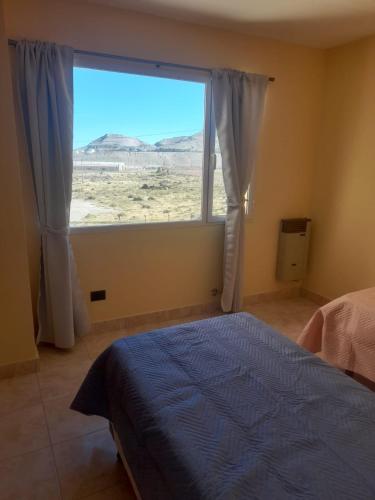 a bedroom with a blue bed and a large window at Apartamentos km4 in Comodoro Rivadavia
