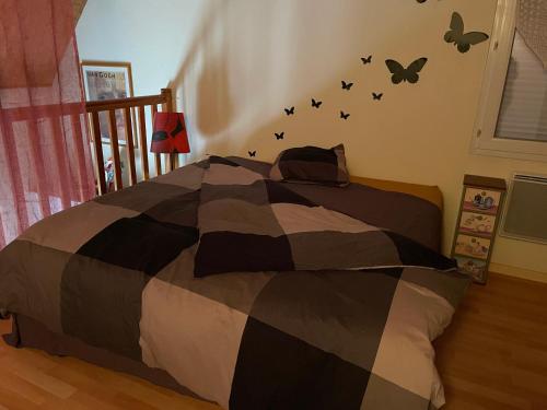 - une chambre avec un lit aux papillons noirs sur le mur dans l'établissement Libertécool, à La Meignanne