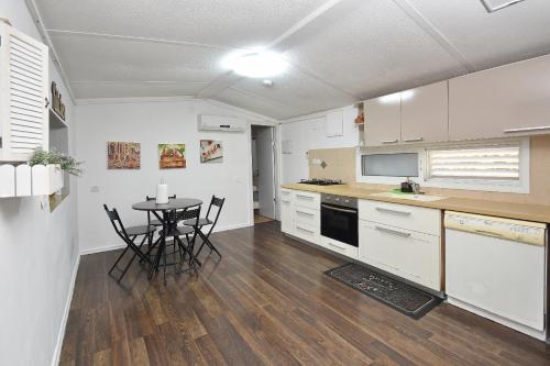 a kitchen with white cabinets and a table with chairs at מיקאסה ג'וי - וילה וסוויטה מדהימות עם בריכה פרטית in Wadi Keren