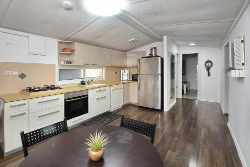 a kitchen with a table and a stainless steel refrigerator at מיקאסה ג'וי - וילה וסוויטה מדהימות עם בריכה פרטית in Wadi Keren