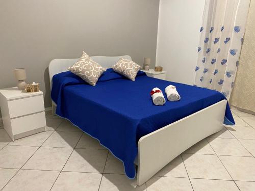 Schlafzimmer mit einem Bett mit blauer Bettwäsche und Kissen in der Unterkunft HomeSea Trapani in Trapani