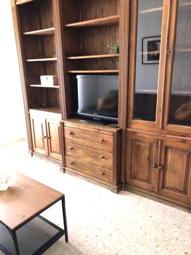 Una sala de estar con un centro de entretenimiento con televisión. en Sol y playa Sanlúcar, en Sanlúcar de Barrameda