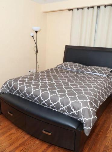 a bed with a black and white comforter in a bedroom at Raised bungalo in Toronto