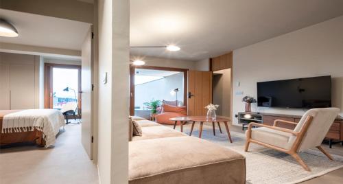 a bedroom with a bed and a living room with a tv at INSUA BEACH HOUSE in Pontevedra