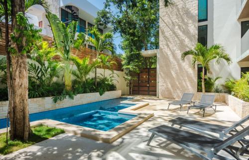 a swimming pool in the middle of a yard with chairs and a building at Sweet Tulum 202 in Tulum