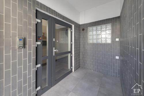 a bathroom with gray tiled walls and a door at Apartament LENA Dziwnówek nad morzem in Dziwnówek