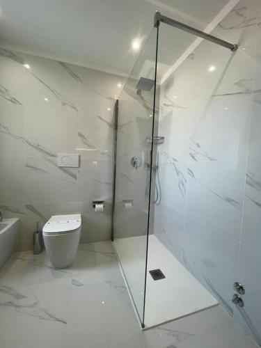 a white bathroom with a shower and a toilet at Hotel Mare in Lignano Sabbiadoro
