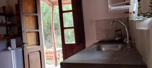 a kitchen with a sink and an open door at La Calabaza Cabaña in Tilcara