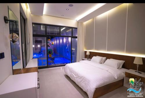 - une chambre avec un grand lit blanc et une fenêtre dans l'établissement شاليهات حكاية الفندفية, à Al Harazat