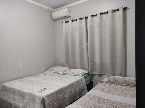 a bedroom with two beds and a curtain at Recanto Aconchego in Rio Verde