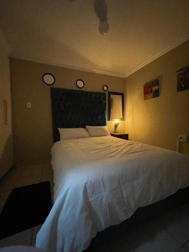 a bedroom with a large white bed and two clocks on the wall at Yello guest house in Vanderbijlpark