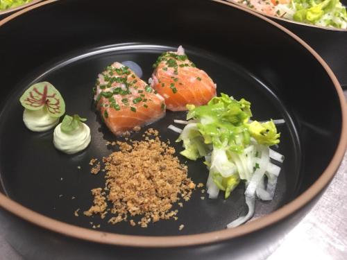 a black plate of food with sushi and vegetables at Landhotel Alberts in Heijenrath