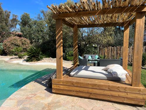 a bed in a wooden gazebo next to a swimming pool at Luxueuse Villa, Hyper centre PORT de PORTO VECCHIO in Porto-Vecchio