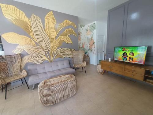 uma sala de estar com um sofá e uma televisão de ecrã plano em The Boho-Chic Staycation House em Dao