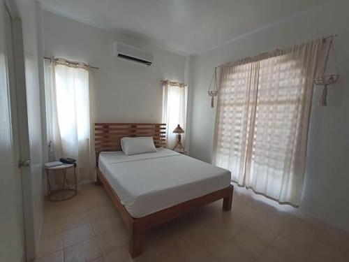 um quarto com uma cama branca e 2 janelas em The Boho-Chic Staycation House em Dao